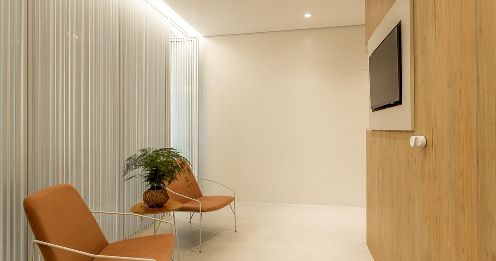 Sala de espera com poltronas de couro caramelo e cortinas claras